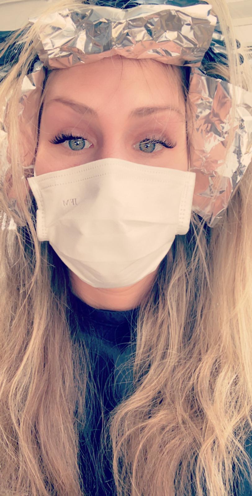 Junge Frau mit Mund-Nasen-Maske beim Friseur