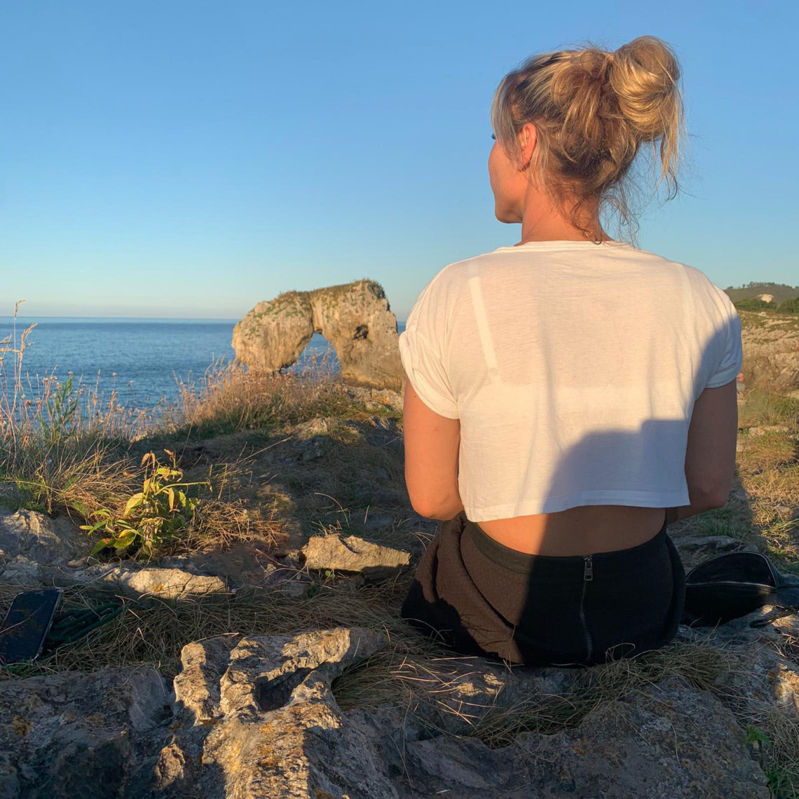 Auf einmal ist Corona ganz nah: Mädchen sitze allein auf Klippen und blickt auf das Meer